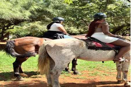Title: Horse riding near Johannesburg Gauteng - Description: Two riders on horseback enjoying a guided trail ride near Johannesburg, surrounded by lush green trees and red African soil β a classic Gauteng outdoor experience.